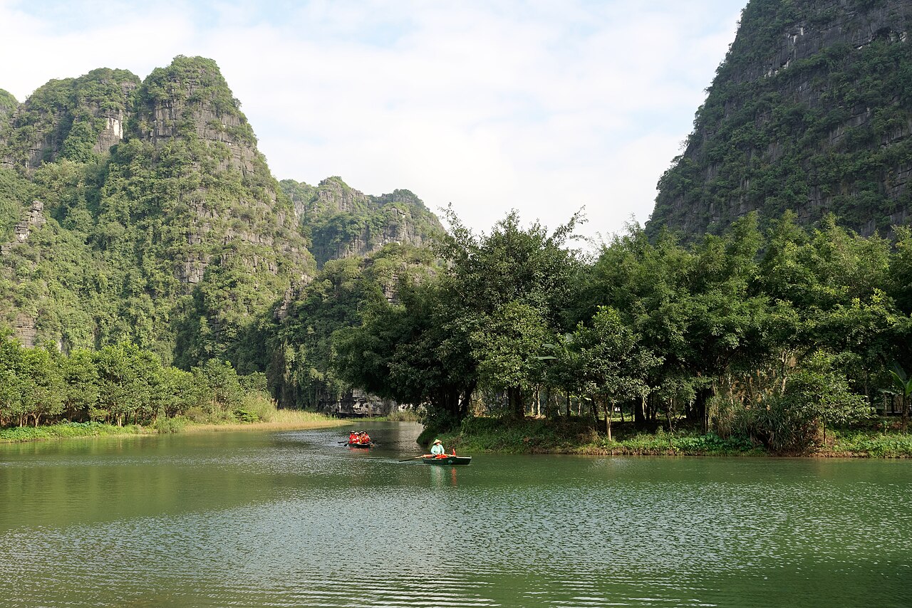 Towering limestone karst peaks reflected in pristine river waterways at Trang An