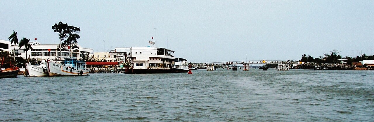 Ben Tre river waterfront with motorized wooden sampans and riverside coconut palms