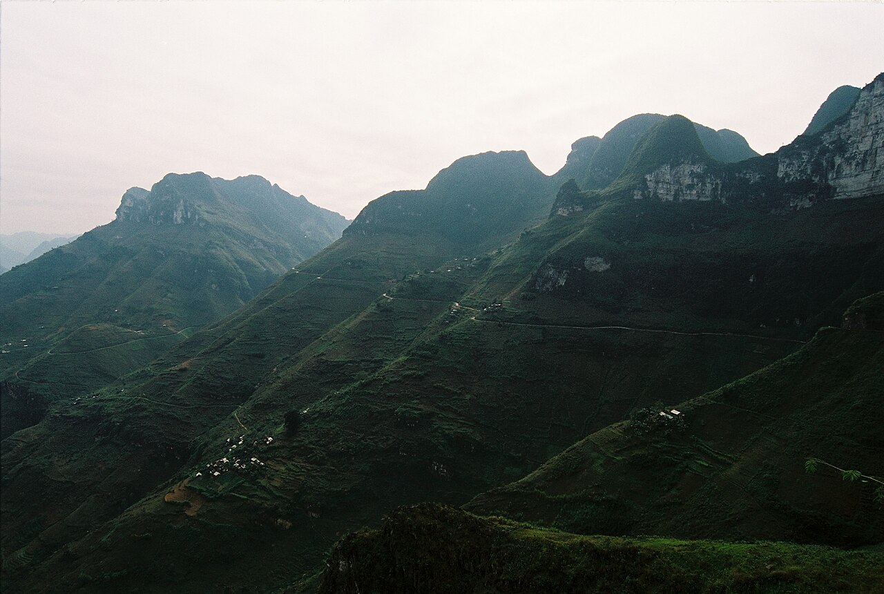 Winding mountain roadway hugging limestone cliff faces in northern Ha Giang province