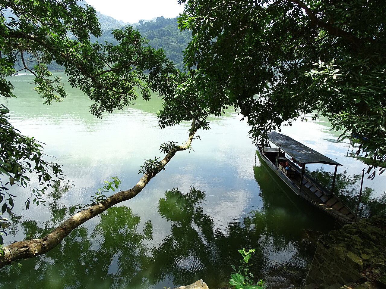 Wooden boat excursion gliding across the calm waters of Ba Be freshwater lake