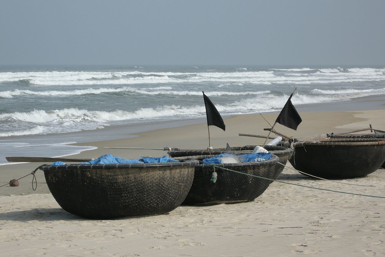 Traditional round woven bamboo basket boats resting on Da Nang white sand beach